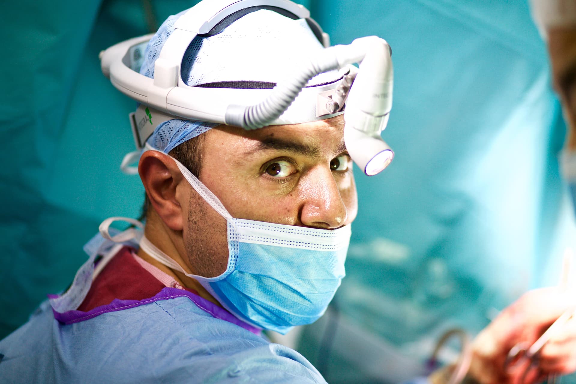 Mr Najib Daulatzai in operating theatre wearing surgical cap, mask, and headlight during colorectal surgery