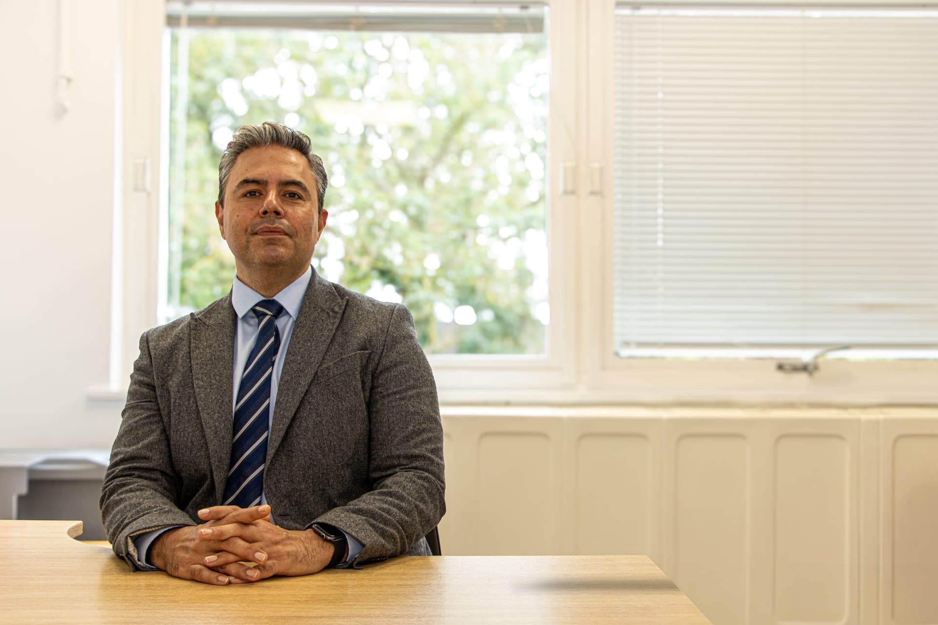 Mr Najib Daulatzai, colorectal and general surgeon in London and Hertfordshire, seated at his desk in professional attire